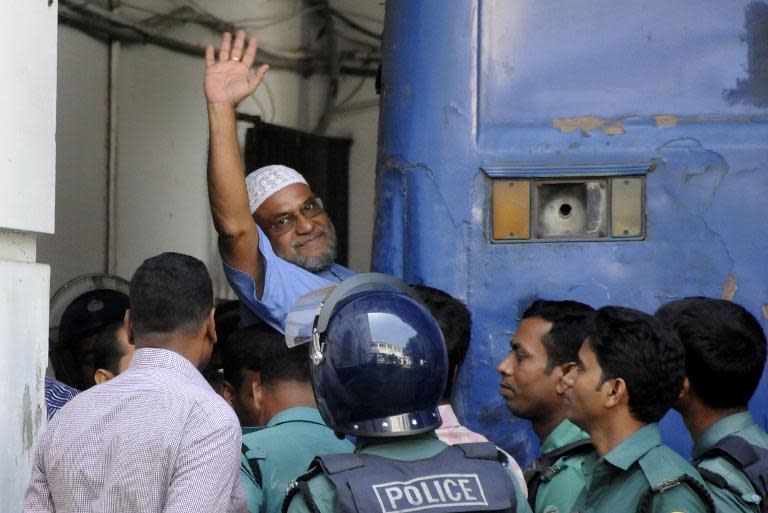 Bangladeshi Jamaat-e-Islami party key official, Mir Quasem Ali, waves as he enters a van outside the International Crimes Tribunal court in Dhaka, on November 2, 2014