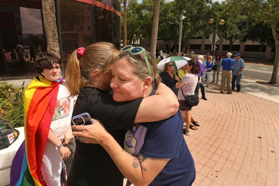As people line up to attend the meeting, Jen Cousins, right, gets a hug from a friend before