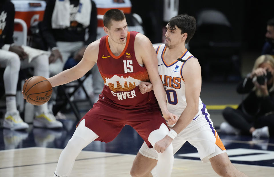 Denver Nuggets center Nikola Jokic, left, moves the ball inside as Phoenix Suns forward Dario Saric defends in the first half of Game 4 of an NBA second-round playoff series Sunday, June 13, 2021, in Denver. (AP Photo/David Zalubowski)