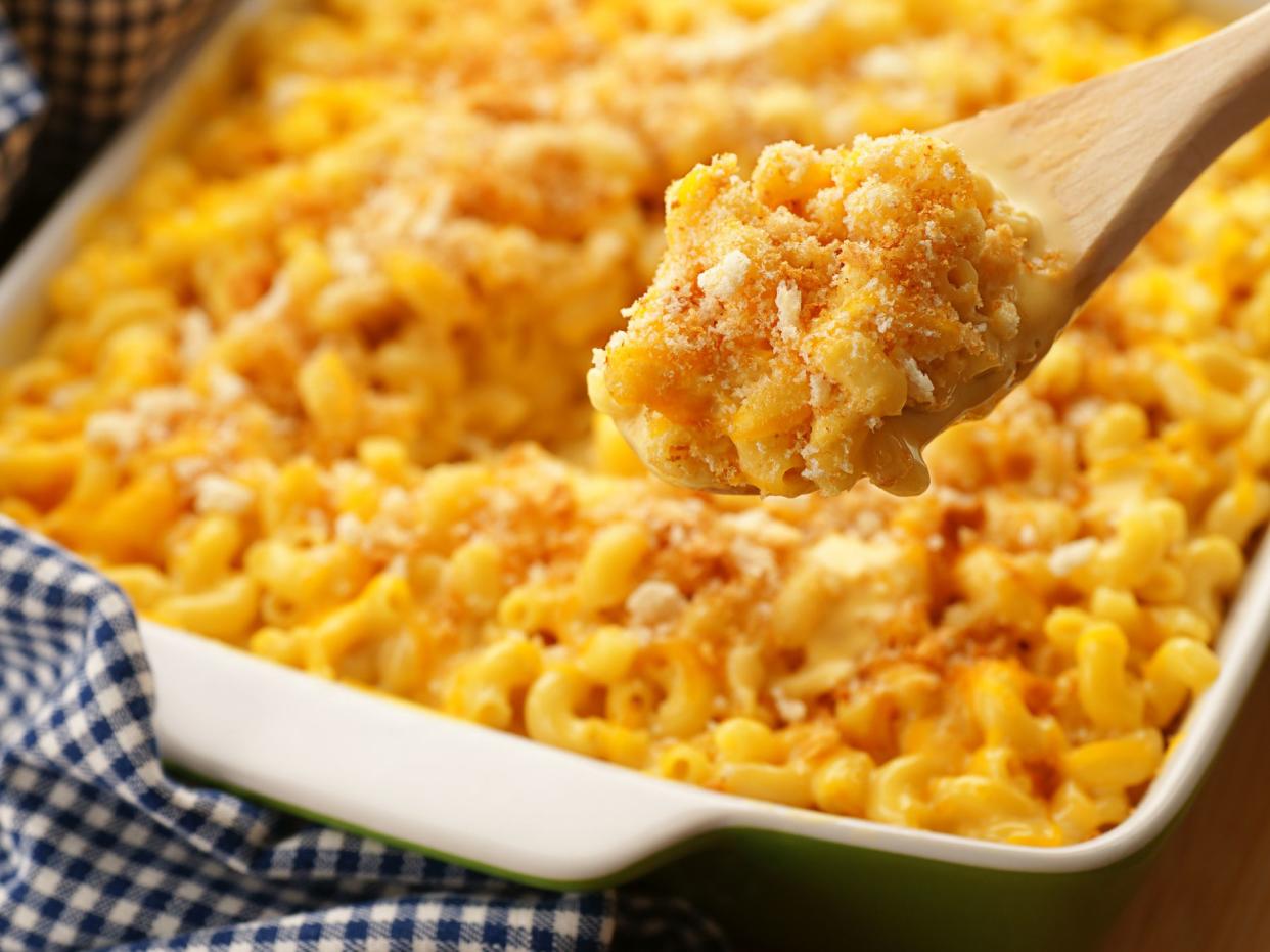 A spoonfull of homestyle baked macaroni and cheese with crispy breadcrumbs and shredded cheddar. Sharp focus on the contents of the spoon.