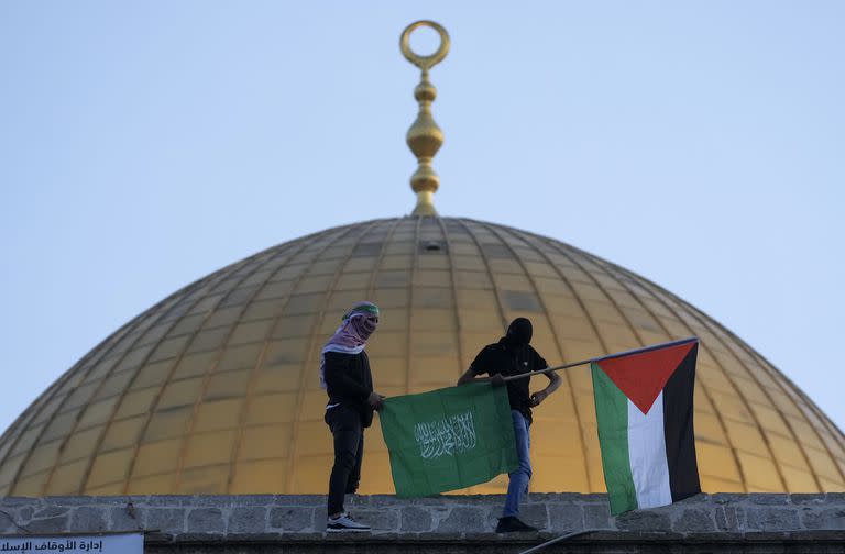 En esta imagen de archivo, dos palestinos enmascarados, con una bandera palestina y otras de Hamas, durante las celebraciones del Eid al-Fitr, cerca de la cúpula de la mezquita Al-Aqsa, en la Ciudad Vieja de Jerusalén, el 2 de mayo de 2022. (AP Foto/Mahmoud Illean, archivo)