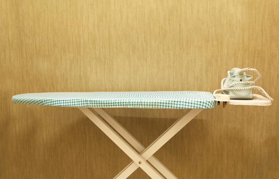 An iron on an green patterned ironing board.