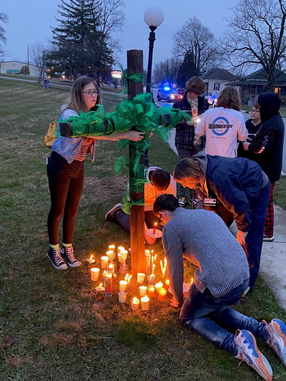 Eaton and Delaware County residents attach green ribbons to a wooden cross Thursday evening at Norseman Park in Eaton. A candlelight vigil was held in honor of Scottie Dean Morris, a 14-year-old Delta Middle School student who hasn't been seen since March 16.