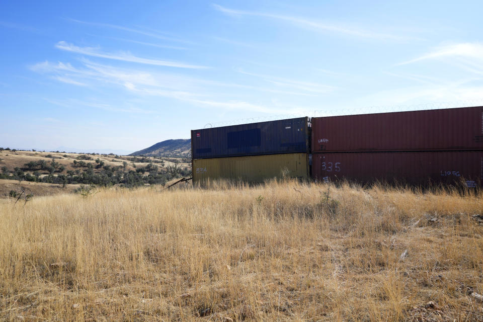 A row of double staked shipping containers abruptly ends at the start of a steep wash along the border between the United States and Mexico in San Rafael Valley, Ariz., Thursday, Dec. 8, 2022. Work crews are steadily erecting hundreds of double-stacked shipping containers along the rugged east end of Arizona’s boundary with Mexico as Republican Gov. Doug Ducey makes a bold show of border enforcement even as he prepares to step aside next month for Democratic Governor-elect Katie Hobbs. (AP Photo/Ross D. Franklin)