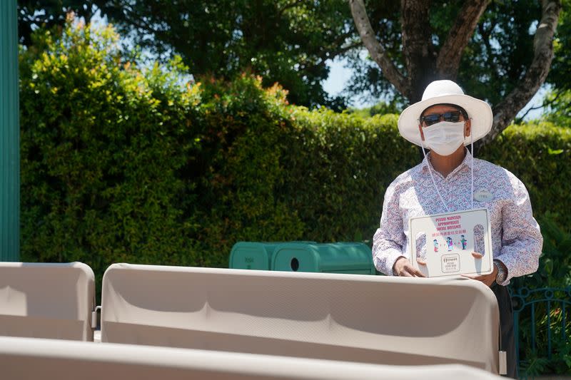 Staff member holds a sign advising visitors to practise social distancing at the Hong Kong Disneyland Resort in Hong Kong