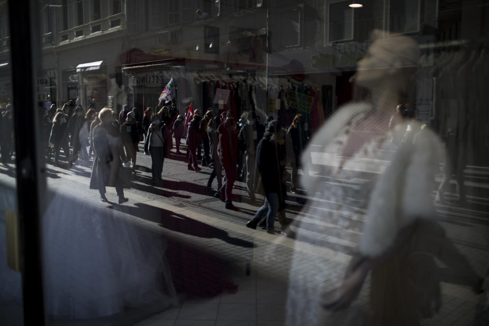 Protesters and students march past shops during a demonstration in Marseille, southern France, Tuesday Jan. 26, 2021. Teachers and university students marched together in protests or went on strike Tuesday around France to demand more government support amid the pandemic. (AP Photo/Daniel Cole)