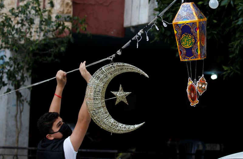 A man puts Ramadan decorations on a street ahead of the Muslim holy month of Ramadan, during a countrywide lockdown over the coronavirus disease (COVID-19) in Beirut