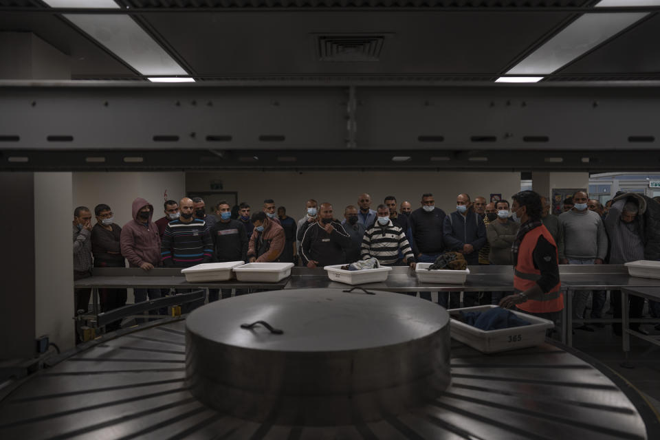 FILE - Palestinian workers crossing from Gaza to Israel wait for their belongings after a security check on the Israeli side of Erez crossing between Israel and the Gaza Strip, March. 27, 2022. For more than two years, the Biden administration has said that Palestinians are entitled to the same measure of “freedom, security and prosperity” enjoyed by Israelis. Instead, they've gotten U.S. aid and permits to work inside Israel and its Jewish settlements. The inconsistency is likely to come up when President Joe Biden visits Israel and the occupied West Bank this week for the first time since assuming office. (AP Photo/Oded Balilty, File)