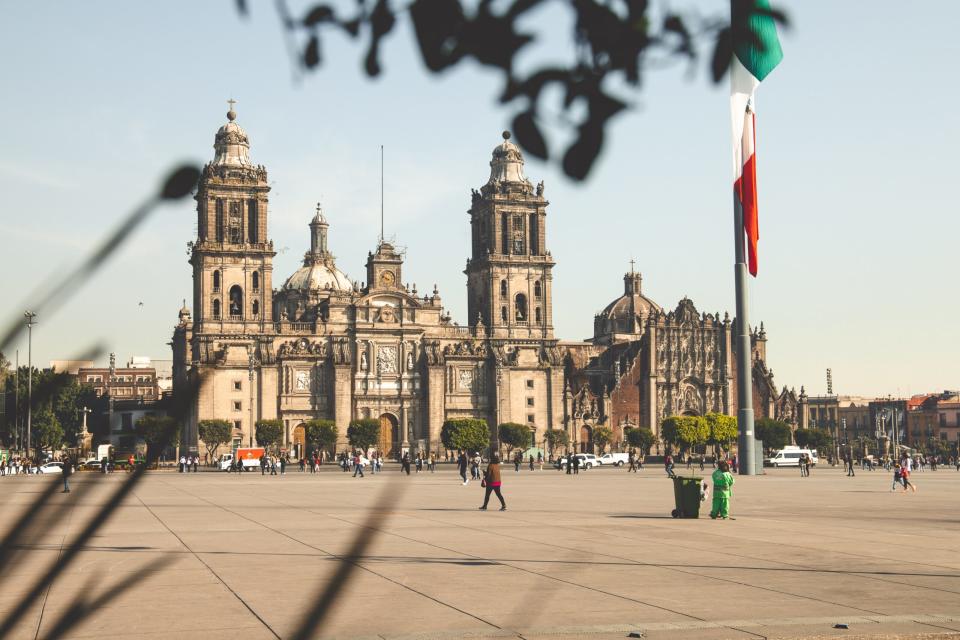 Read more about the best travel advisories to use when potentially traveling to areas that may not be fully safe. 
pictured: the bustling Mexico City with its national flag posted in front of a historical building
