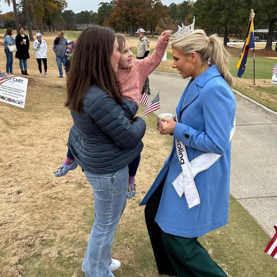 Taylor Loyd crouches down so a young girl can touch her crown at a recent appearance she made at an event as Miss North Carolina.