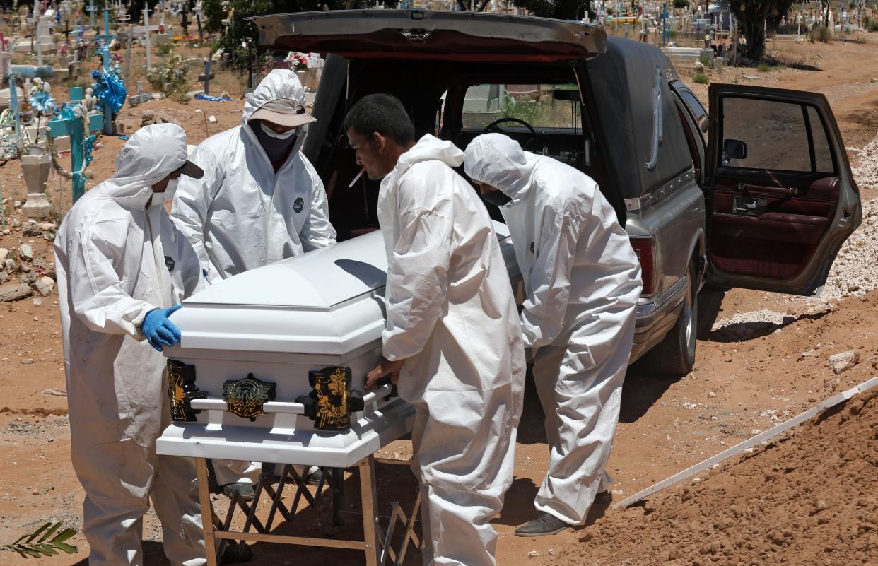 Cemetery workers unload the coffin of a woman from the hearse for her burial in an area of the San Rafael municipal pantheon designated for victims of the novel coronavirus, COVID-19, in Ciudad Juarez, Chihuahua State, Mexico, on May 17, 2020. - Local authorities prohibit families of COVID-19 victims from entering the municipal pantheon, so cemetery workers bury the deceased with no relatives present. (Photo by Herika MARTINEZ / AFP) (Photo by HERIKA MARTINEZ/AFP via Getty Images)