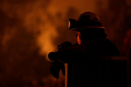 Cal Fire firefighter Zach Hallums watches as fire burns in a canyon below homes as crews battle the Carr Fire, west of Redding. REUTERS/Fred Greaves