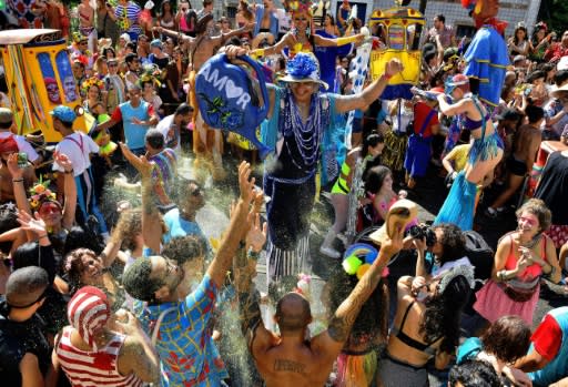 A performer showers revellers with glitter in a street party during the annual 'Ceu Na Terra bloco,' in the run up to Rio's carnival, on February 15