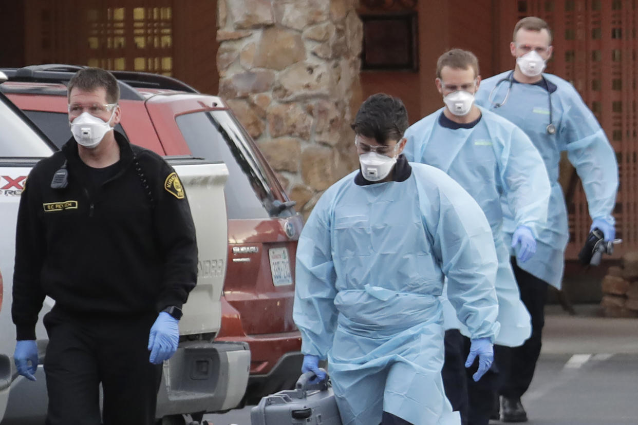 Kirkland Fire and Rescue ambulance workers walk back to a vehicle after a patient was loaded into an ambulance, Tuesday, March 10, 2020, at the Life Care Center in Kirkland, Wash., near Seattle. The nursing home is at the center of the outbreak of the new coronavirus in Washington state. (AP Photo/Ted S. Warren)