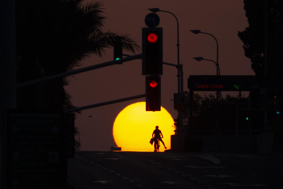 A person rides a bicycle as the sun sets on an empty street during the first day of three-week lockdown in Tel Aviv, Israel, Friday, Sept. 18, 2020. (AP Photo/Ariel Schalit)