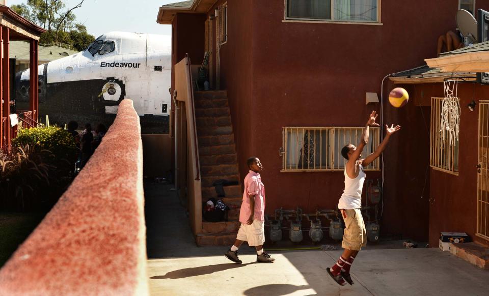 Traymond Harris y Ryan Hudge juegan baloncesto en el patio de su casa mientras el transbordador espacial Endeavour es remolcado en dirección a su destino final, el centro de Ciencia de California, en el sur de Los Angeles. (Photo by Wally Skalij-Pool/Getty Images)