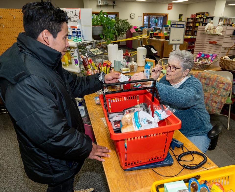 Kay Robers, the site manager of the Community Space in Whitewater, hands Edwin-Josue Pres-Ruiz of Nicaragua a card with the hours the facility is open. Pres-Ruiz, a father of two young daughters, came to Whitewater to work and send money home to his family.