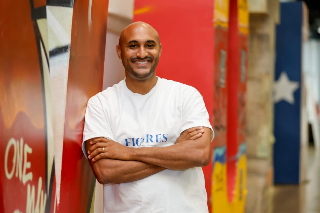 A man with his arms folded and smiling at the camera