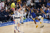 Dallas Mavericks guard Luka Doncic shoots a 3-point basket over the stretched arms of Golden State Warriors forward Andrew Wiggins during the second half of Game 4 of the NBA basketball playoffs Western Conference finals, Tuesday, May 24, 2022, in Dallas. (AP Photo/Tony Gutierrez)