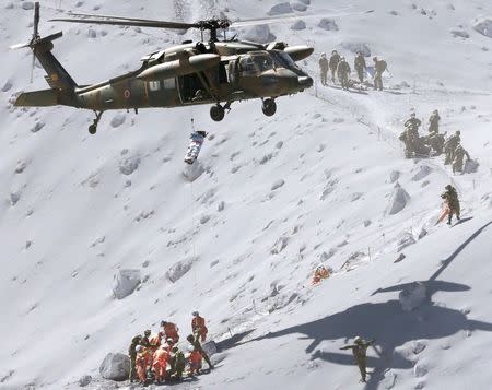 A hiker is lifted by a rescue helicopter of Japan Self-Defense Force (JSDF) during a rescue operation at Mt. Ontake, which straddles Nagano and Gifu prefectures, central Japan September 28, 2014, in this photo taken and released by Kyodo. REUTERS/Kyodo