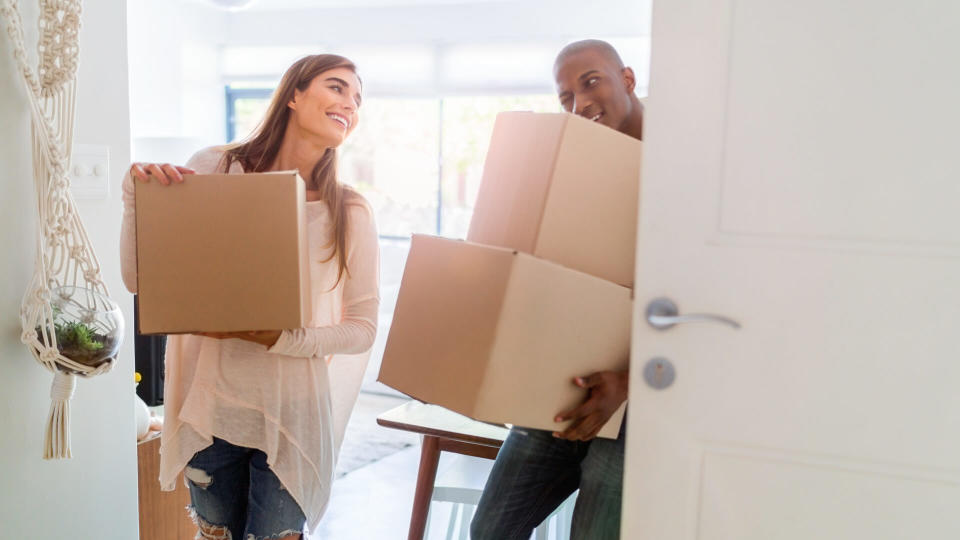 Multi-ethnic couple carrying cardboard boxes.