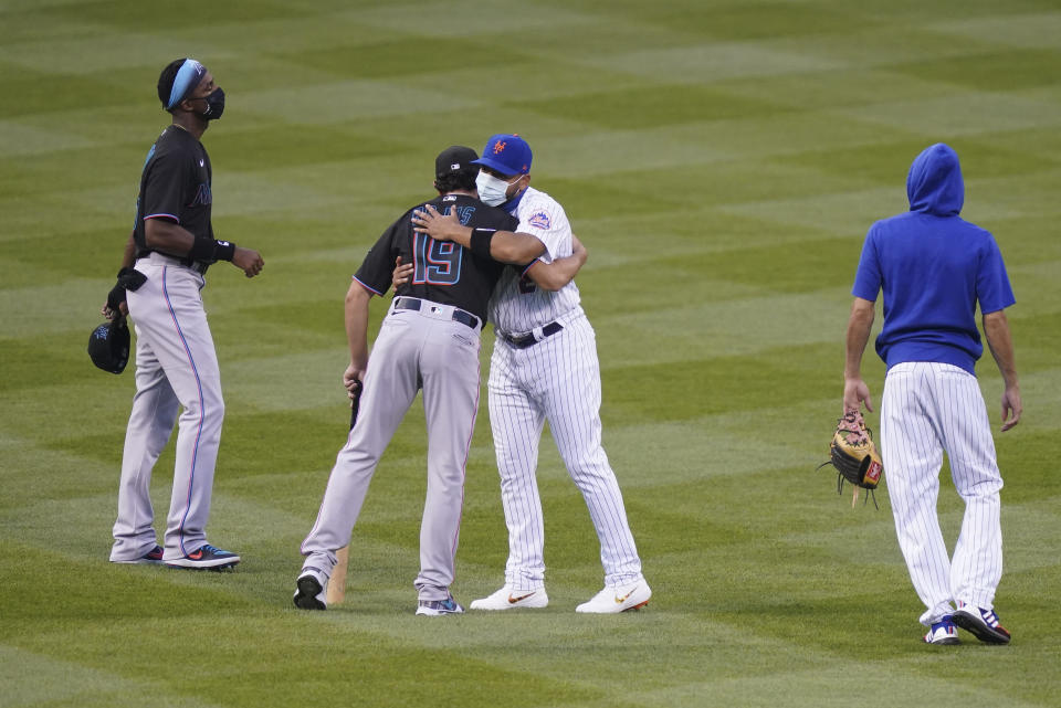 New York Mets left fielder Dominic Smith (2) and Miami Marlins shortstop Miguel Rojas (19) hug in center field before both teams walk off in protest at the start of their baseball game, Thursday, Aug. 27, 2020, in New York. The teams jointly walked off the field after a moment of silence, draping a Black Lives Matter T-shirt across home plate as they chose not to start their scheduled game Thursday night. (AP Photo/John Minchillo)