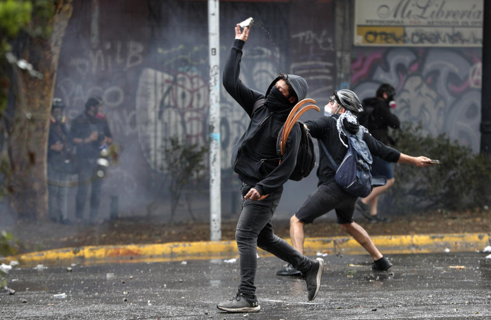 Demonstrators throw missiles at the police during an anti-government protest in Santiago, Chile, Monday, Nov. 4, 2019. Chile has been facing weeks of unrest, triggered by a relatively minor increase in subway fares. The protests have shaken a nation noted for economic stability over the past decades, which has seen steadily declining poverty despite persistent high rates of inequality. (AP Photo/Esteban Felix)