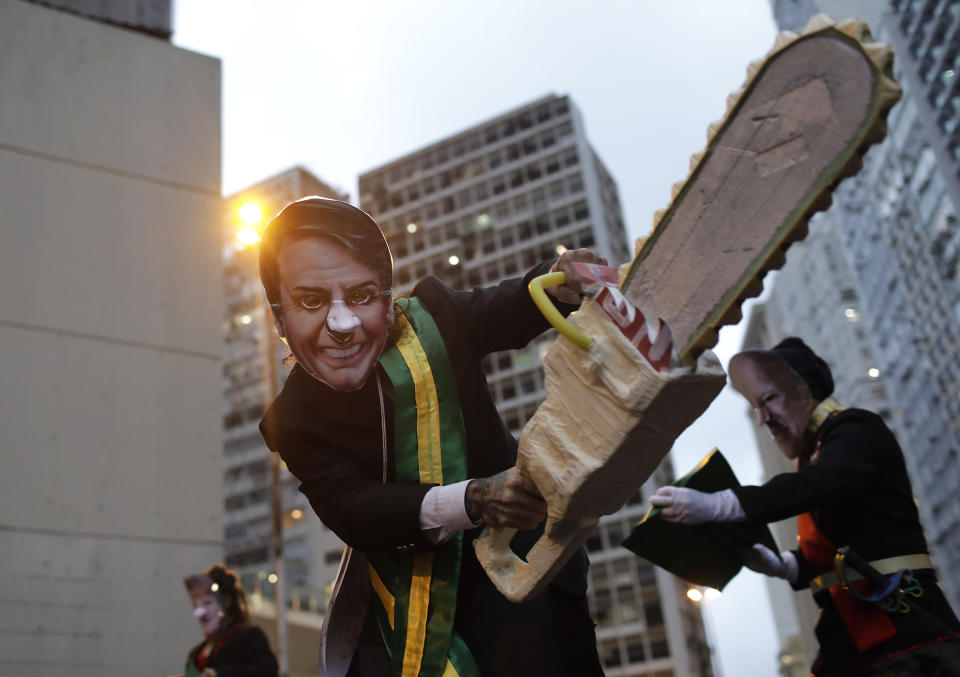A demonstrator wearing a mask with the likeness of Brazil's President Jair Bolsonaro and brandishing a fake chainsaw, protests in defense of the Amazon, in Rio de Janeiro, Brazil, Thursday, Sept. 5, 2019. The Brazilian Amazon saw almost 31 thousand fires in August, the highest for the month since 2010, according to Brazil's National Institute for Space Research. (AP Photo/Silvia Izquierdo)