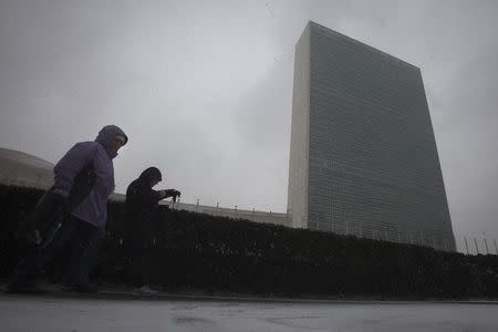 People walk past the United Nations building as it snows in the Manhattan borough of New York January 26, 2015. REUTERS/Carlo Allegri