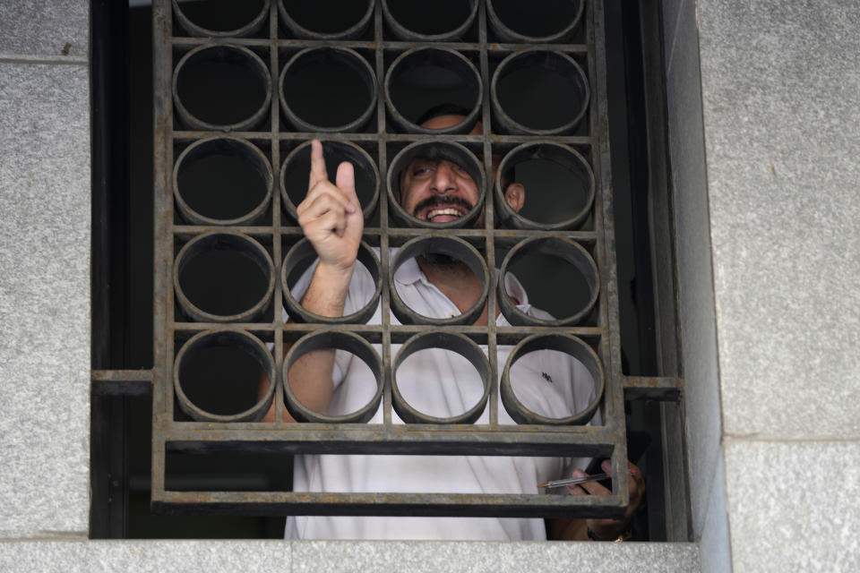 Abed Soubra, que tenía rehenes en una sucursal bancaria en un intento por sacar fondos de su cuenta, habla con la prensa desde el interior del banco el 16 de septiembre del 2022, en Beirut. (AP Foto/Bilal Hussein)