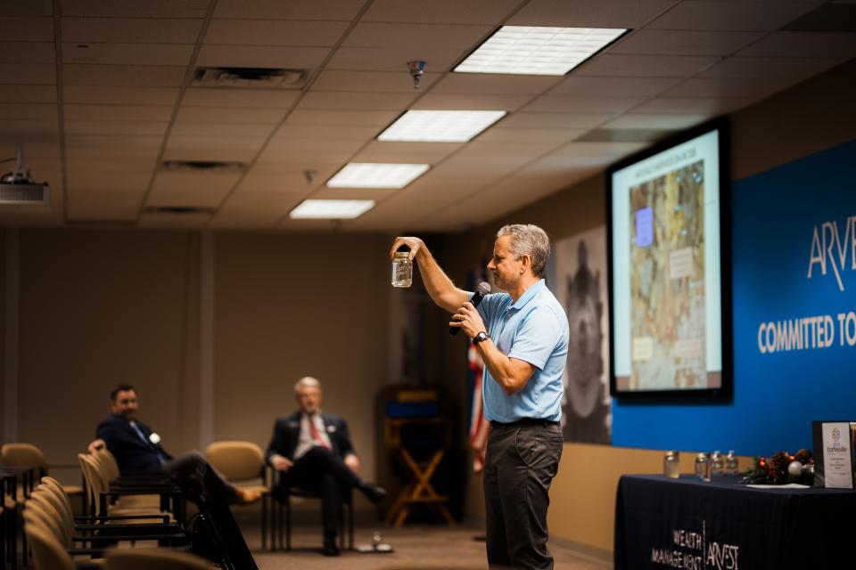 Water Utilities Director Terry Lauritsen holds up a glass jar filled with water from the sewer treatment plant and compared it to a glass of water straight from the Caney River. Lauritsen argues the treated water is cleaner than the Caney.