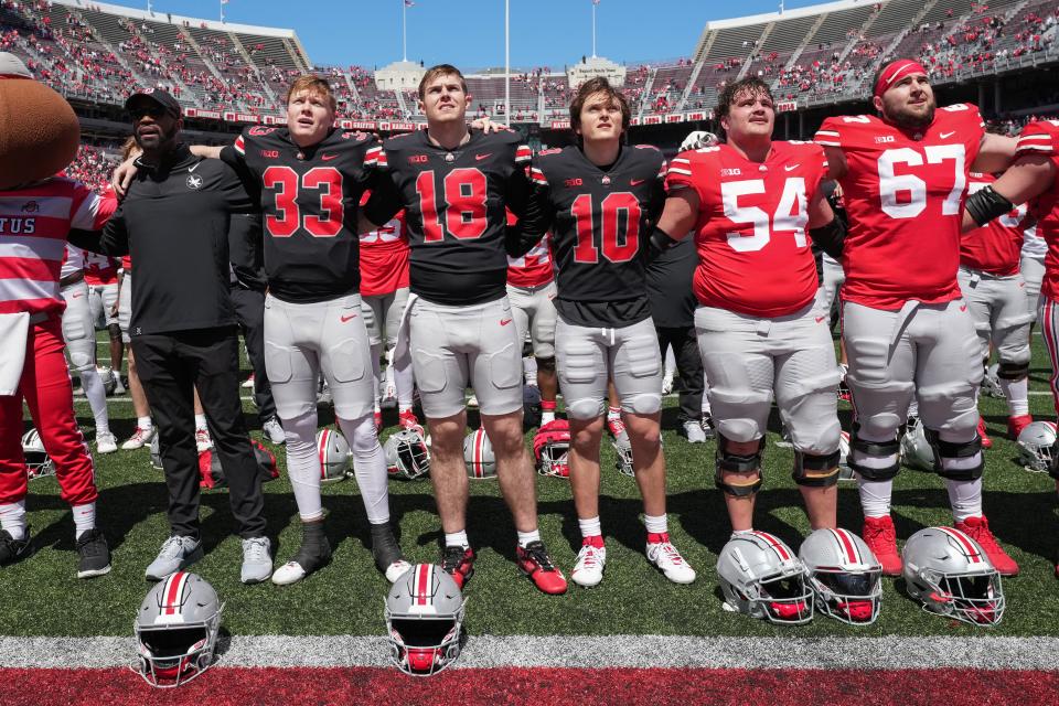 Apr 13, 2024; Columbus, OH, USA; Ohio State Buckeyes quarterback Devin Brown (33), Ohio State Buckeyes quarterback Will Howard (18), Ohio State Buckeyes quarterback Julian Sayin (10), Ohio State Buckeyes offensive line Toby Wilson (54) and Ohio State Buckeyes offensive line Austin Sievreveld (67) sign carmen ohio after the Ohio State football spring game at Ohio Stadium.