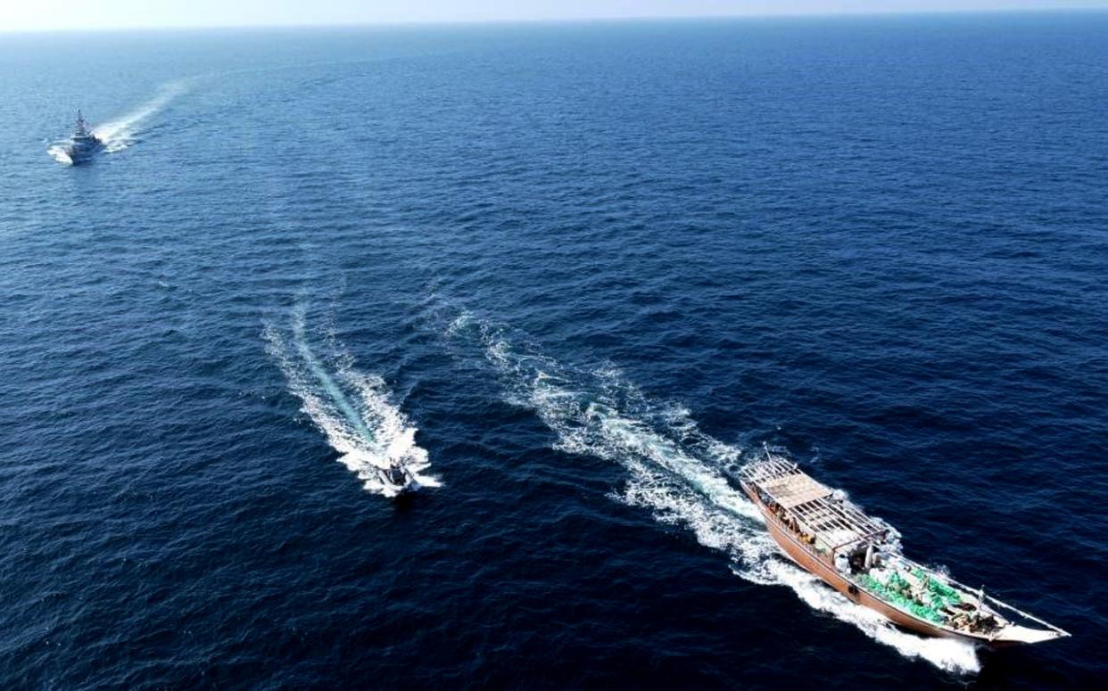 In this photo released by the U.S. Navy, a stateless fishing vessel, right, is interdicted by USS vessels while transiting international waters in the North Arabian Sea on Dec. 20, 2021. The U.S. Navy seized a large cache of assault rifles and ammunition being smuggled by a fishing ship from Iran likely bound for war-ravaged Yemen, it said late Wednesday, Dec. 22. (U.S. Navy via AP)