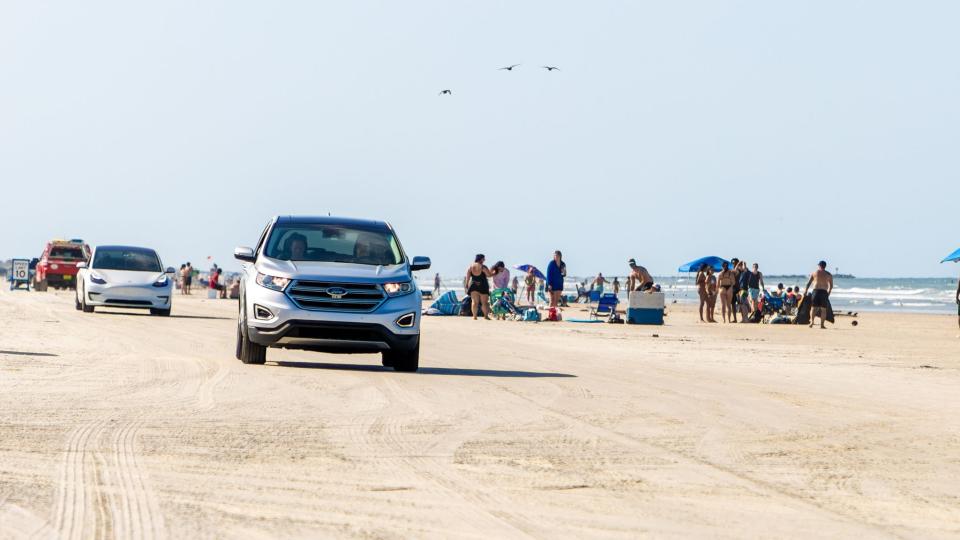 A car drives down the beach in New Smyrna Beach, FL.