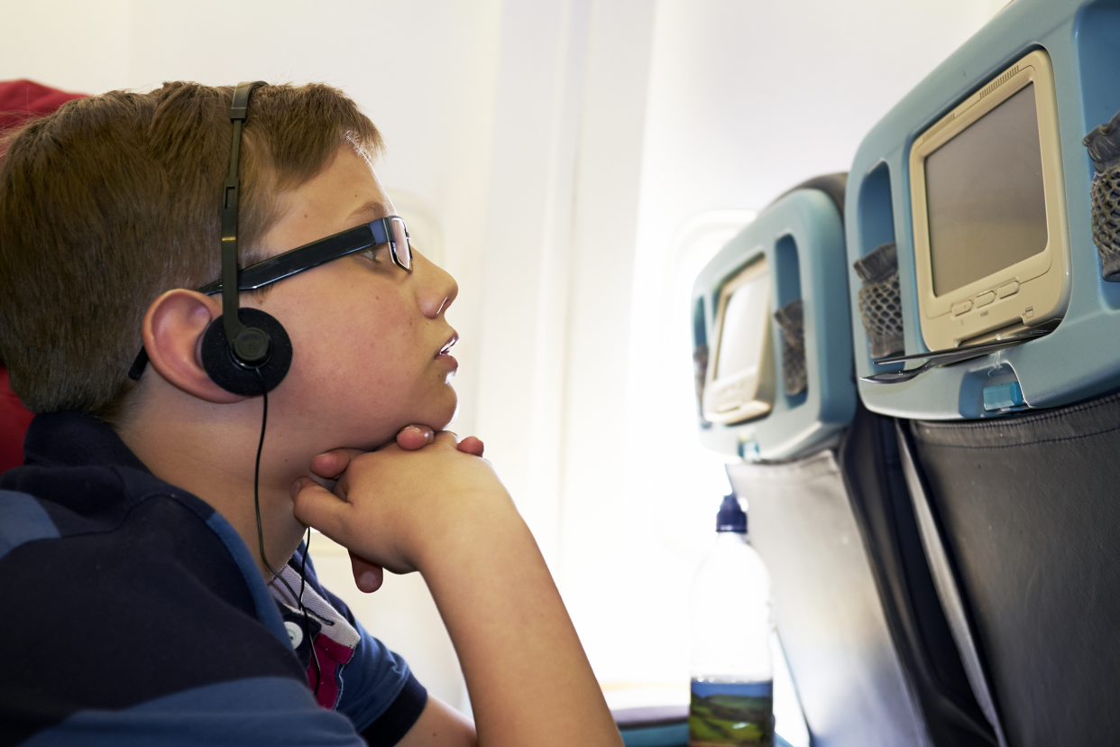 Boy watching a movie on an airplane screen