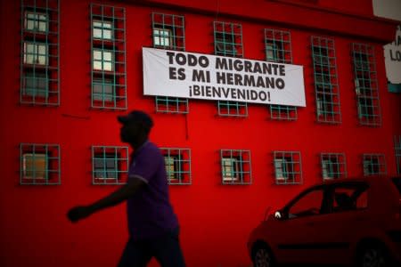 FILE PHOTO: An Haitian immigrant walks past a banner that reads