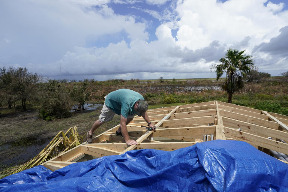 Mark Poindexter puts a tarp on the damaged roof of his home in in Gulf Breeze, La., in the aftermath of Hurricane Laura, Saturday, Aug. 29, 2020. (AP Photo/Gerald Herbert)