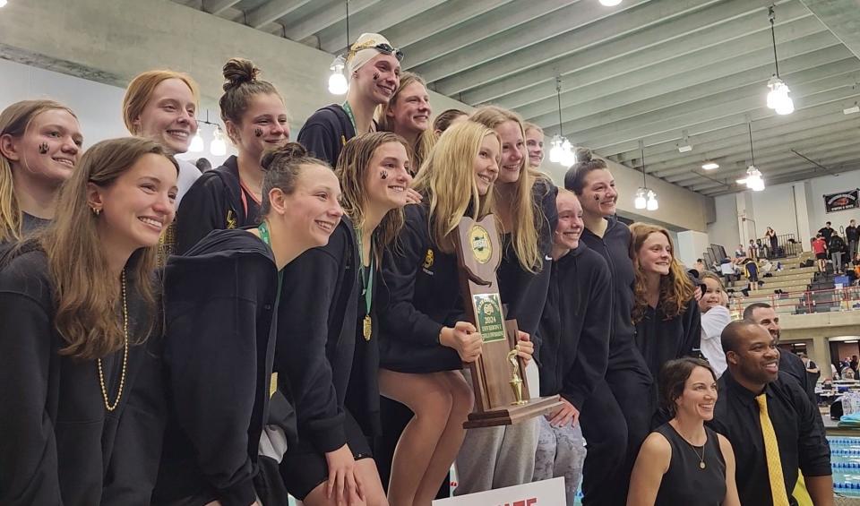The Upper Arlington swimming and diving program is mourning the death of assistant coach Gary Grant, shown at lower right as the girls team poses with the Division I state championship trophy Feb. 24 at Branin Natatorium in Canton. Grant, a former Ohio State swimmer, worked with both the boys and girls teams and coached with the Upper Arlington Swim Club.