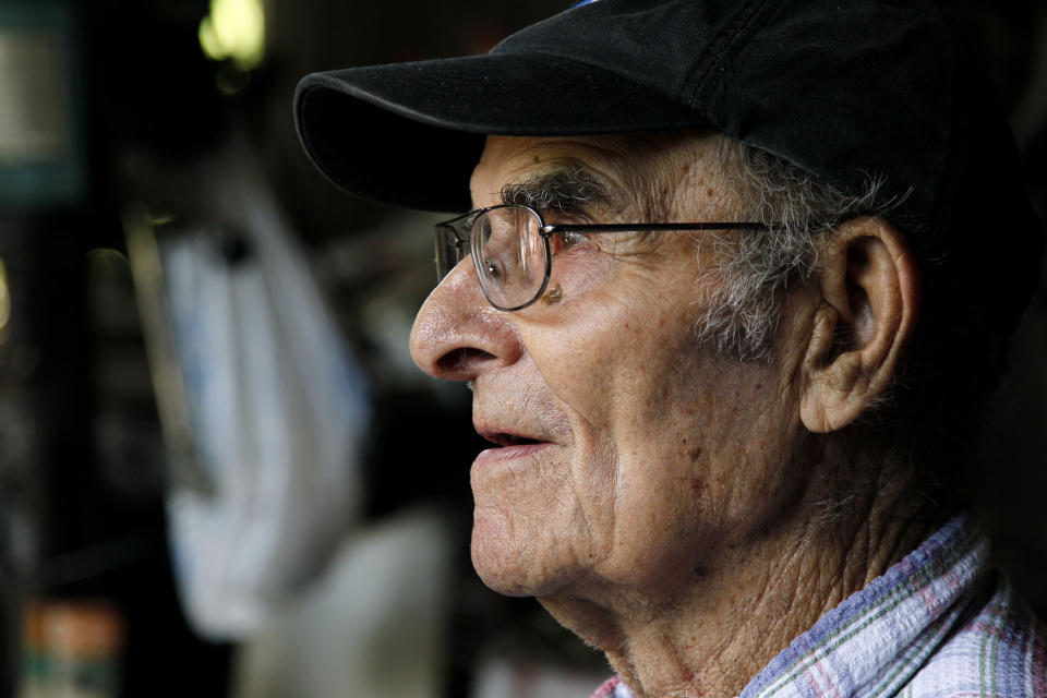 In this Thursday, June 21, 2012 file photo, whirligig artist Vollis Simpson sits outside his shop in Lucama, N.C. Simpson, a self-taught artist famed for his whimsical, wind-powered whirligigs, has died. He was 94. Simpson's wife, Jean, told the Wilson Daily Times that her husband died in his sleep Friday, May 31, 2013. (AP Photo/Gerry Broome)