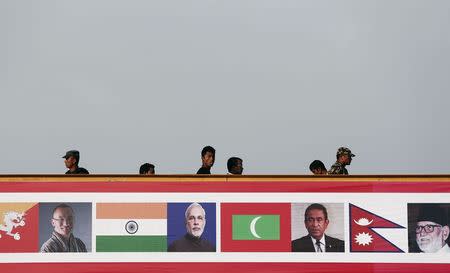 Nepalese police stand guard on an overhead bridge as pedestrians walk past outside a venue where India's Prime Minister Narendra Modi is addressing a conference in Kathmandu November 25, 2014. REUTERS/Adnan Abidi