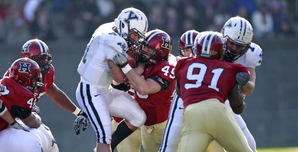 ORG XMIT: MAGC101 Yale Bulldogs running back Alex Thomas (41) is stopped by Harvard Crimson line backer Alex Gedeon (49) during the first half of a NCAA college football game on Saturday, November 20, 2010 in Cambridge, Mass.   (AP Photo/Greg M. Cooper)