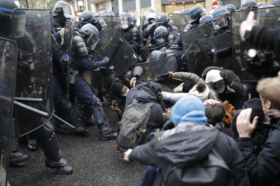 Riot police officers control a group of protesters during a protest against a proposed bill , Saturday, Dec.12, 2020 in Paris. The bill's most contested measure could make it more difficult for people to film police officers. It aims to outlaw the publication of images with intent to cause harm to police. The provision has caused such an uproar that the government has decided to rewrite it. Critics fear the law could erode press freedom and make it more difficult to expose police brutality. (AP Photo/Lewis Joly)