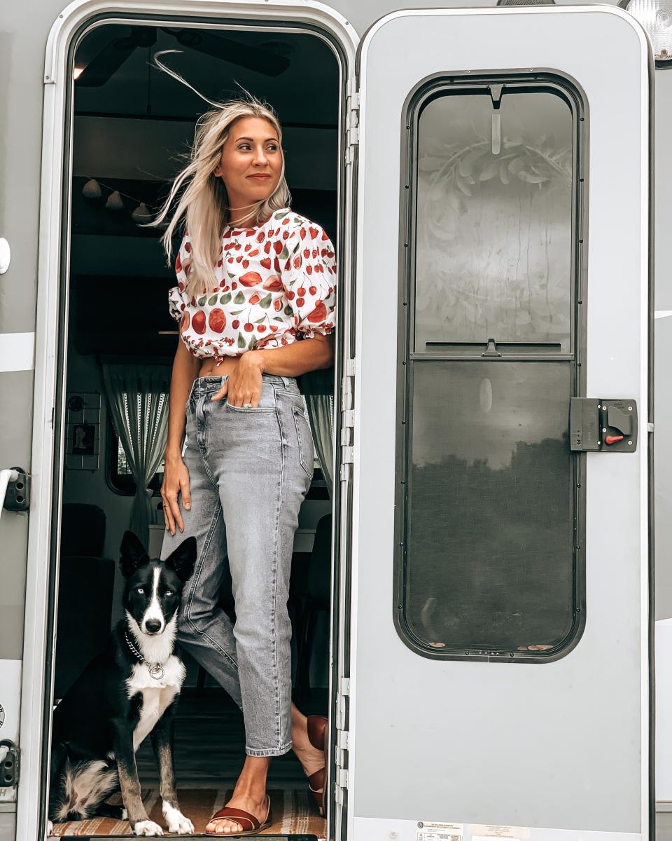 A mom standing in front of RV door beside dog