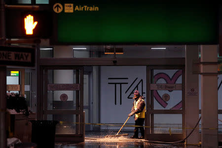A worker attempts to remove water following a water main break in the arrivals area of Terminal 4 at John F. Kennedy International Airport in New York City, U.S. January 7, 2018. REUTERS/Andrew Kelly