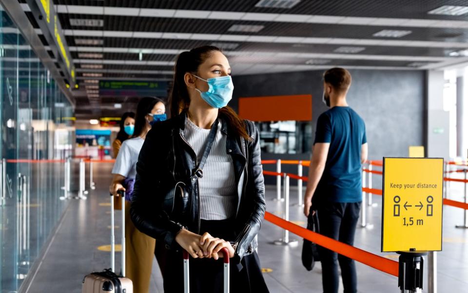 Passengers wearing masks queue in line at the airport - izusek/Getty