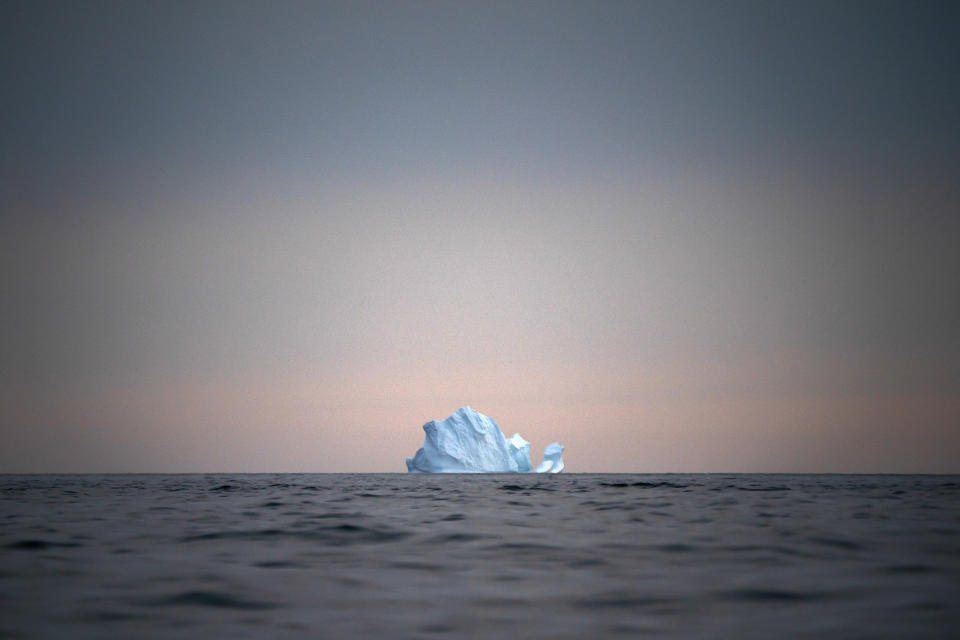 In this Aug. 15, 2019, photo, a large Iceberg floats away as the sun sets near Kulusuk, Greenland. Greenland is where Earth's refrigerator door is left open, where glaciers dwindle and seas begin to rise. Scientists are hard at work there, trying to understand the alarmingly rapid melting of the ice. For Greenland is where the planet's future is being written. (AP Photo/Felipe Dana)