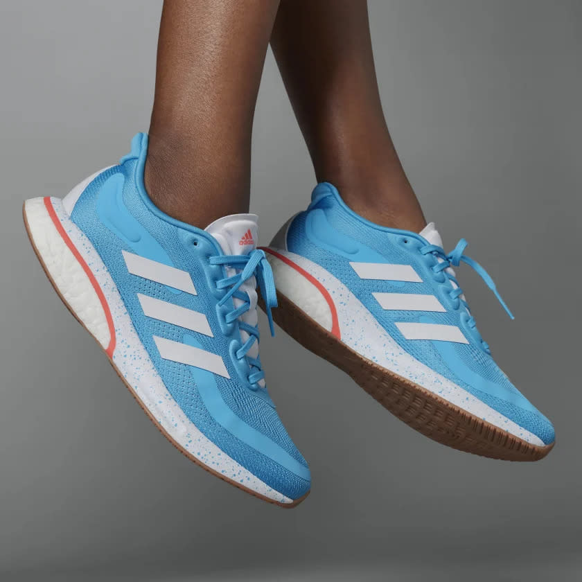 Model wearing blue, white and red sneakers while jumping