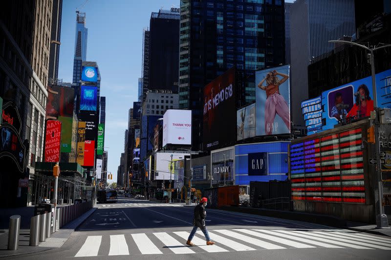 A man crosses 7th Avenue in nearly deserted Times Square during the outbreak of the coronavirus disease (COVID-19) in New York
