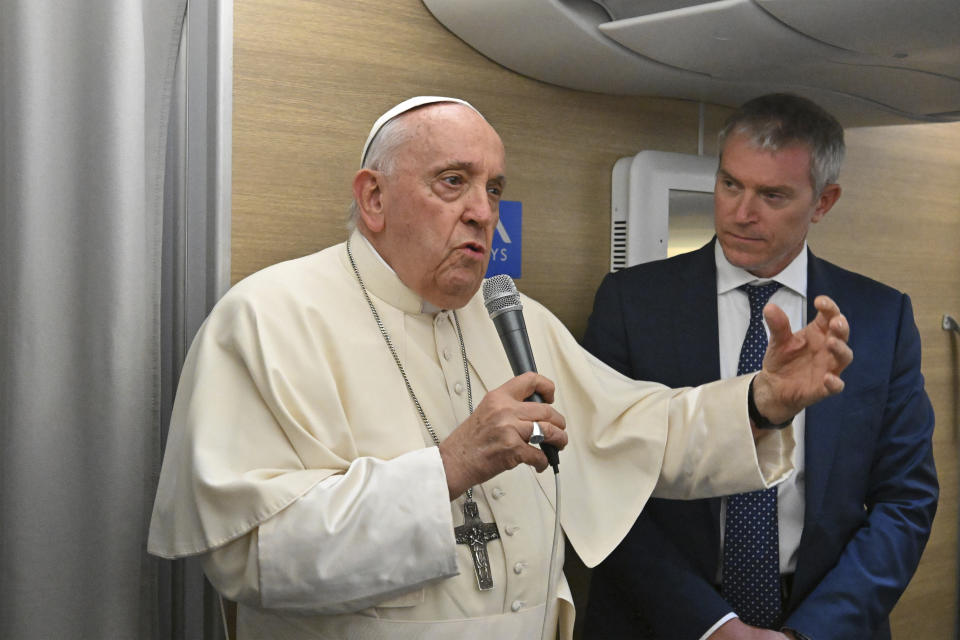 Pope Francis, left, is flanked by his spokeperson Matteo Bruni as he talks with journalist on their flight to Mongolia, Thursday, Aug. 31, 2023. Francis will be the first pope to visit Mongolia. (AP Photo/Alberto Pizzoli, pool)