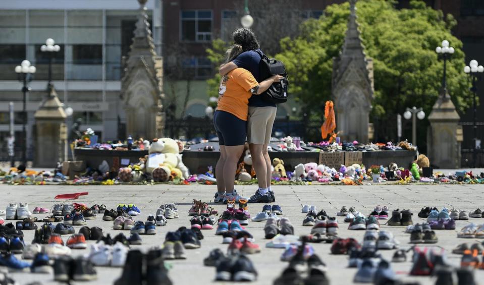 <span class="caption">Two people embrace in front of the Centennial Flame on Parliament Hill, in Ottawa at a memorial for the 215 children whose remains were found at the grounds of the former Kamloops Indian Residential School. </span> <span class="attribution"><a class="link " href="https://www.cpimages.com/CS.aspx?VP3=DamView&VBID=2RLQ2JT3Y1MDG&SMLS=1&RW=1324&RH=686#/DamView&VBID=2RLQ2JTIWH209&PN=1&WS=SearchResults" rel="nofollow noopener" target="_blank" data-ylk="slk:THE CANADIAN PRESS/Justin Tang;elm:context_link;itc:0;sec:content-canvas">THE CANADIAN PRESS/Justin Tang</a></span>